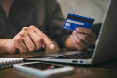 Kredi kartı tutan ve laptop için online yazarak işadamı 