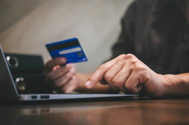 Kredi kartı tutan ve laptop için online yazarak işadamı 