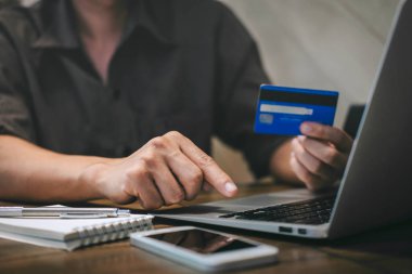 Kredi kartı tutan ve laptop için online yazarak işadamı 