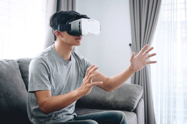 Young asian man having fun wearing playing virtual reality heads
