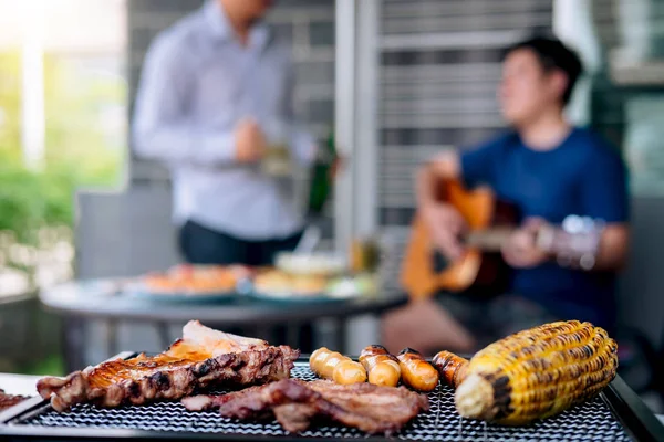Group of friends Two young man enjoying grilled meat and play gu — Stock Photo, Image