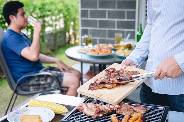 Group of friends Two young man enjoying grilled meat and raise a — Stock Photo, Image