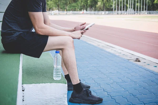 Joven atleta de fitness hombre descansando en el banco con botella de agua — Foto de Stock