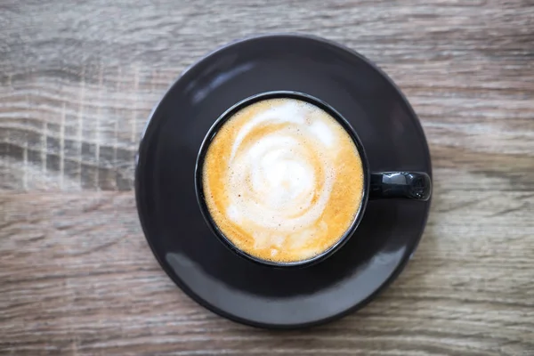 Black Cup of coffee with milk foam so delicious on old wooden ta — Stock Photo, Image