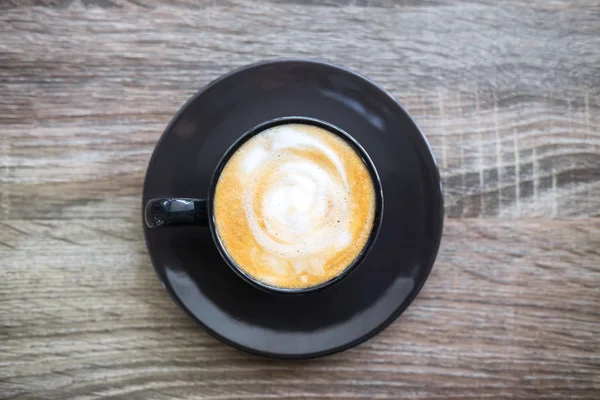 Xícara de café preto com espuma de leite tão delicioso na velha ta de madeira — Fotografia de Stock