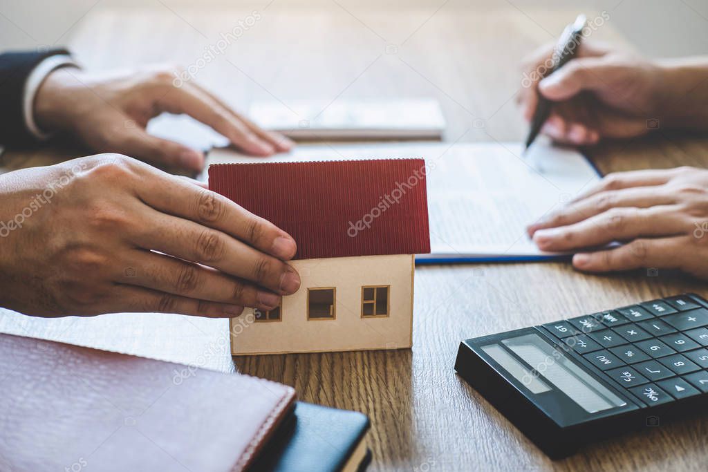 Estate agent giving house and keys to client after signing agree