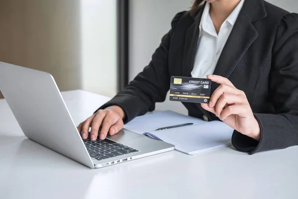 Ділова жінка споживач тримає кредитну картку і друкує на ноутбуці — стокове фото