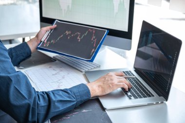 Borsa konsepti, borsa simsarı ekran ekranı ile çalışan ve analiz eden borsacı, sunulan verilere işaret ediyor ve bir borsada anlaşma yapıyor, iş adamı çevrimiçi hisse senedi ticareti yapıyor.
