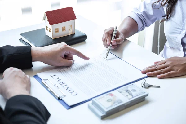 Estate agent broker pointing contract form to client signing agreement contract real estate with approved mortgage application form, buying or concerning mortgage loan offer for and house insurance.