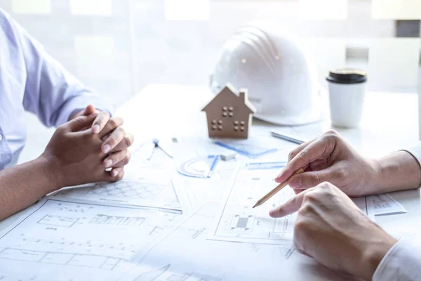 Team of construction engineering or architect partner discuss a blueprint while checking information on drawing and sketching meeting for architectural project with engineering equipment tool.