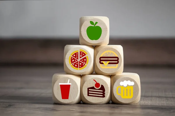 Cubes and dice with fast food smybols and on top an apple for diet
