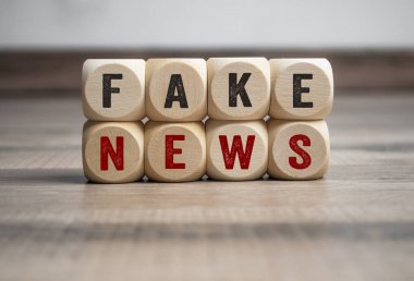 Cubes and dice with fake news on wooden background clipart