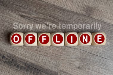 Cubes and dice on wooden background with message Sorry were temporarily offline clipart