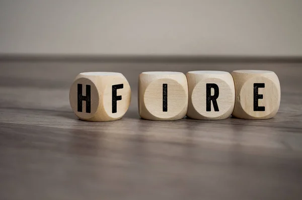 Cubes and dice with words hire and fire on wooden background