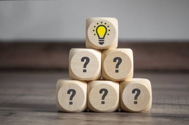 Piramit soru etiketleri ve ampul ile küp ve zar yapılmış - ahşap arka plan üzerinde sorun ve çözüm için metafor