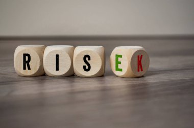 Cubes and dice with the words rise and risk on wooden background