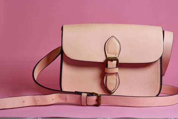 El çantası ve parfüm pembe bir arka plan üzerinde
