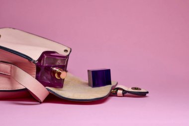 El çantası ve parfüm pembe bir arka plan üzerinde