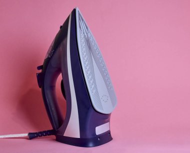 Pembe bir arka plan üzerinde modern elektrikli demir