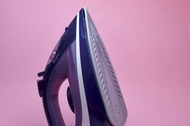 Pembe bir arka plan üzerinde modern elektrikli demir