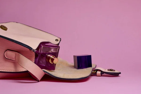 El çantası ve parfüm pembe bir arka plan üzerinde