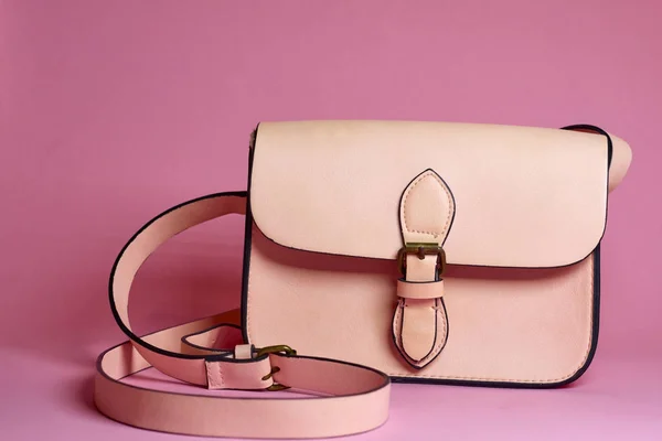 El çantası ve parfüm pembe bir arka plan üzerinde