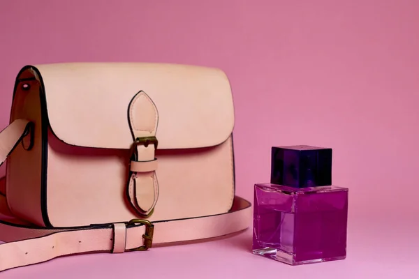 El çantası ve parfüm pembe bir arka plan üzerinde