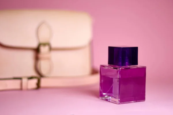 El çantası ve parfüm pembe bir arka plan üzerinde