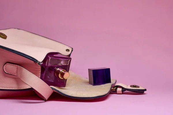 El çantası ve parfüm pembe bir arka plan üzerinde