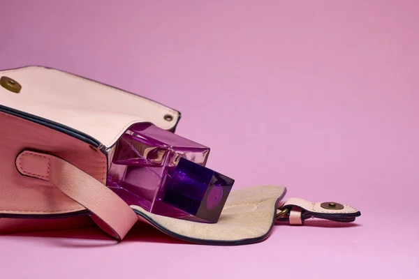 El çantası ve parfüm pembe bir arka plan üzerinde
