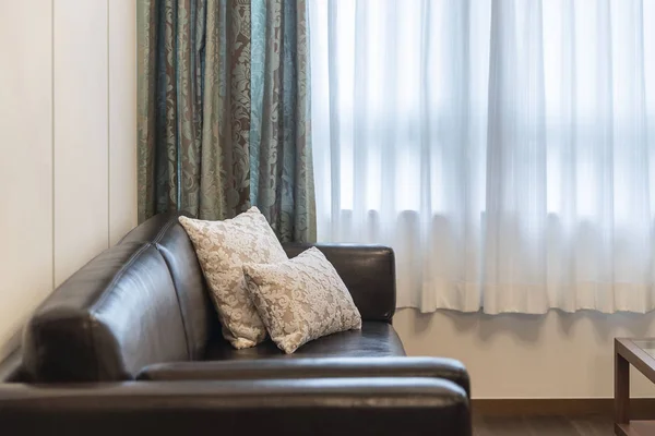 自宅のリビングルームにクッション付きの黒い革張りのソファ — ストック写真