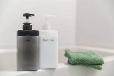 Küvetin kenarına yerleştirilen küçük havlular ile plastik şişeler, şampuan ve sabun