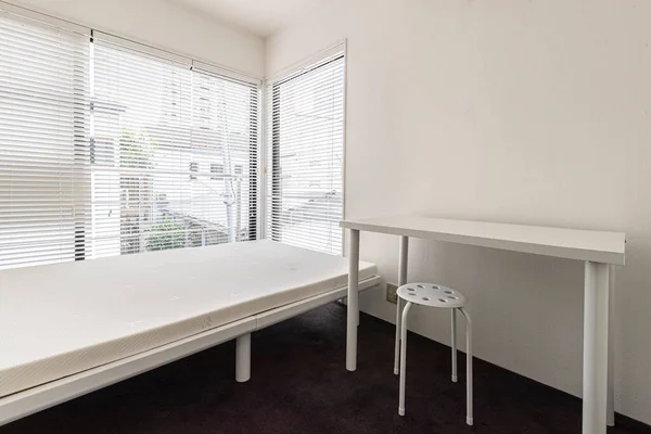 Empty Single bed and white table in small bedroom at apartment