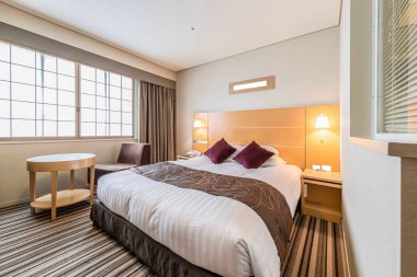 Parlak ve ferah bir yatak odasında büyük boy bir yatak.