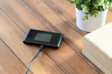 Kahverengi ahşap masada şarj aleti olan cep kablosu.