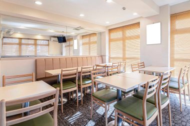 Otelde küçük bir kahvaltı odasında boş masa ve sandalyeler.