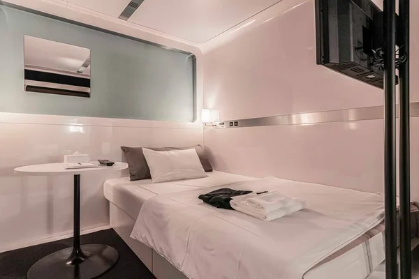 A queen-sized bed inside a premium capsule room at a modern capsule hotel in Japan