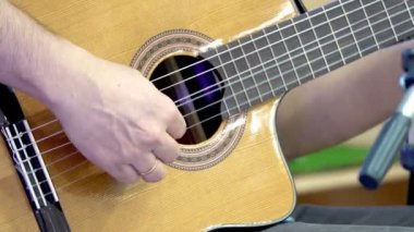 Sahnede klasik gitar çalan bir adamın ellerini yakın