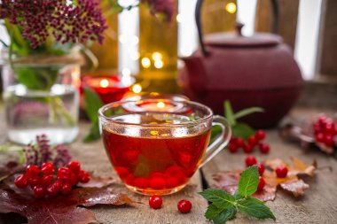  fincan sıcak çay ahşap bir masa, mumlar, sonbahar çiçek, yaprak ve meyveleri Rabinas bir buket ile. Sessizlik, rahatlama ve konfor evde kavramının. Sonbahar arka plan