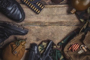 Askeri askeri üniforma, silah, tabanca kılıfı, tabanca, şişesi, çizmeler ahşap arka plan üzerinde. Kopya space.Military arka plan ile düz yatıyordu üstten görünüm