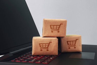 Online alışveriş / e-ticaret ve teslimat hizmeti kavramı: kağıt karton ile bir alışveriş sepeti veya logo üstünde a laptop klavye trolley, perakendeci siteler internet üzerinden gelen müşteriler sipariş şeyler gösteriyor.
