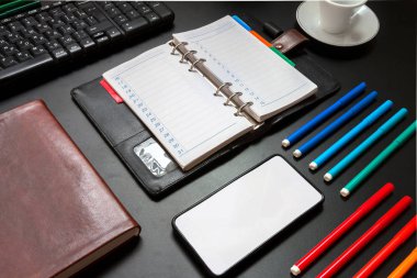 İş amaçlı aksesuarları masaüstünüzde bir desen koyulur. Klavye, notebook, kahve, işaretçileri karanlık bir arka plan üzerinde.