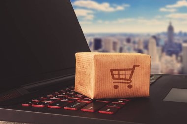 Online alışveriş / e-ticaret ve teslimat hizmeti kavramı: kağıt karton ile bir alışveriş sepeti veya logo üstünde a laptop klavye trolley, perakendeci siteler internet üzerinden gelen müşteriler sipariş şeyler gösteriyor.
