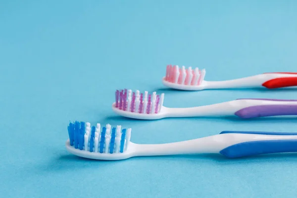 concept of dental health. Three multicolored toothbrushes and toothpaste on a blue background. Design, health care, healthy hygiene