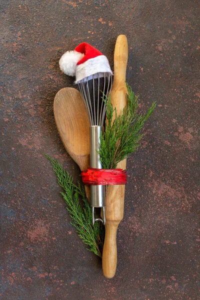 Accessories for cooking with whisk in Santa cap, rolling pin and coniferous branches