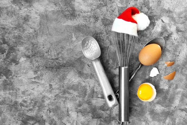Tools for cooking with whisk in Santa cap and eggs