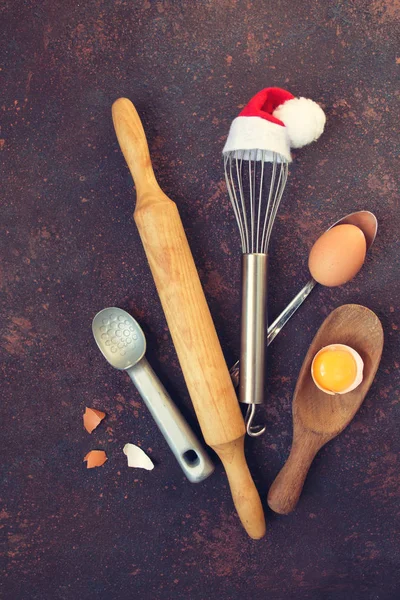 Tools for cooking with whisk in Santa cap, rolling pin and eggs