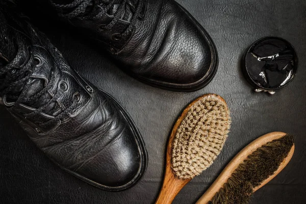 Shoe care. Shoe wax, boot and brushes on wooden surface. Edited image with vintage effect