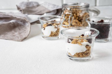 Grnola, Kuru üzüm, süt cam kavanoz ve hafif bir arka plan üzerinde kopya alanı ile süper bir yemek için çeşitli malzemeler