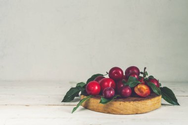 Ahşap açık renkli yapraklarda ile taze kırmızı Erik